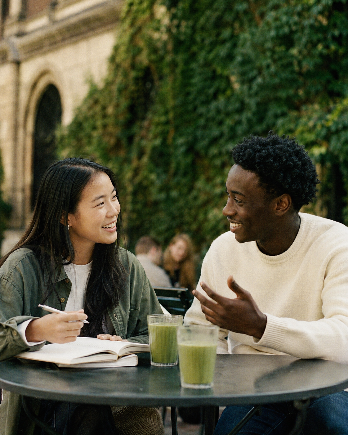 Two students exchanging ideas over matcha at an outdoor campus café